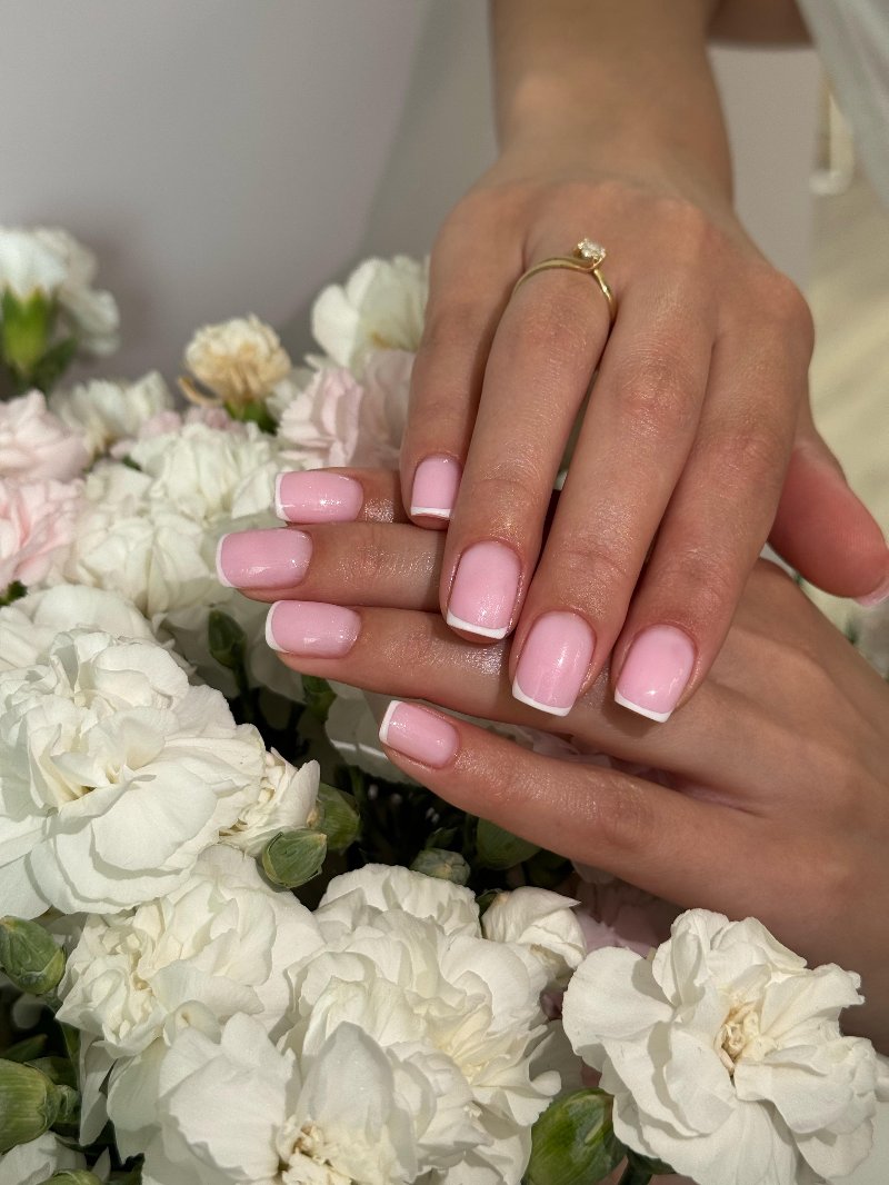 Roze nagels naast witte bloemen